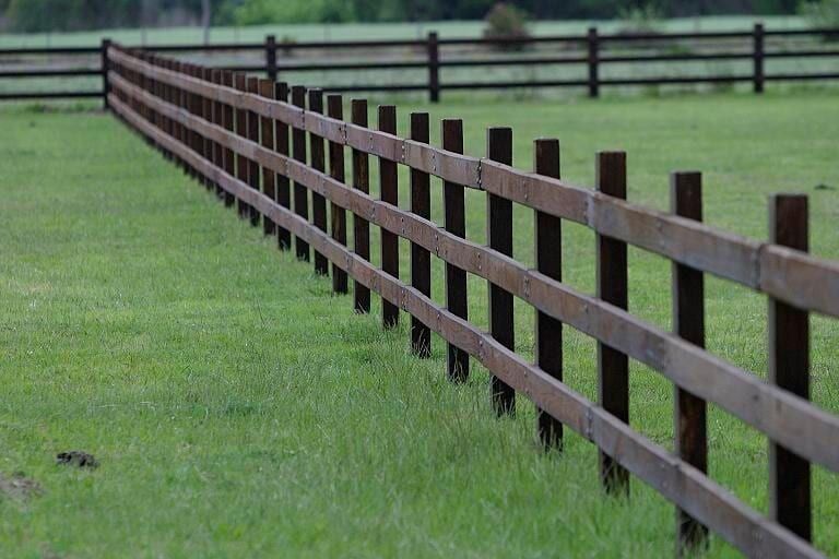 A Long Wooden Fence Surrounds a Grassy Field — Osborne Fencing in Bundanoon, NSW