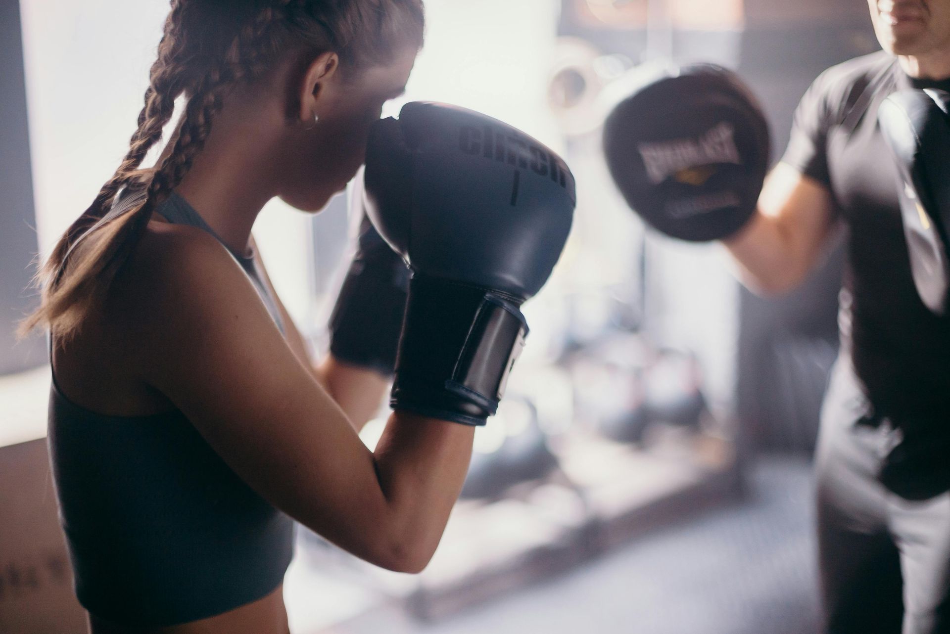 Een vrouw bokst met een man in een sportschool.