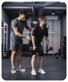 Een man helpt een vrouw met het tillen van een halter in een sportschool.