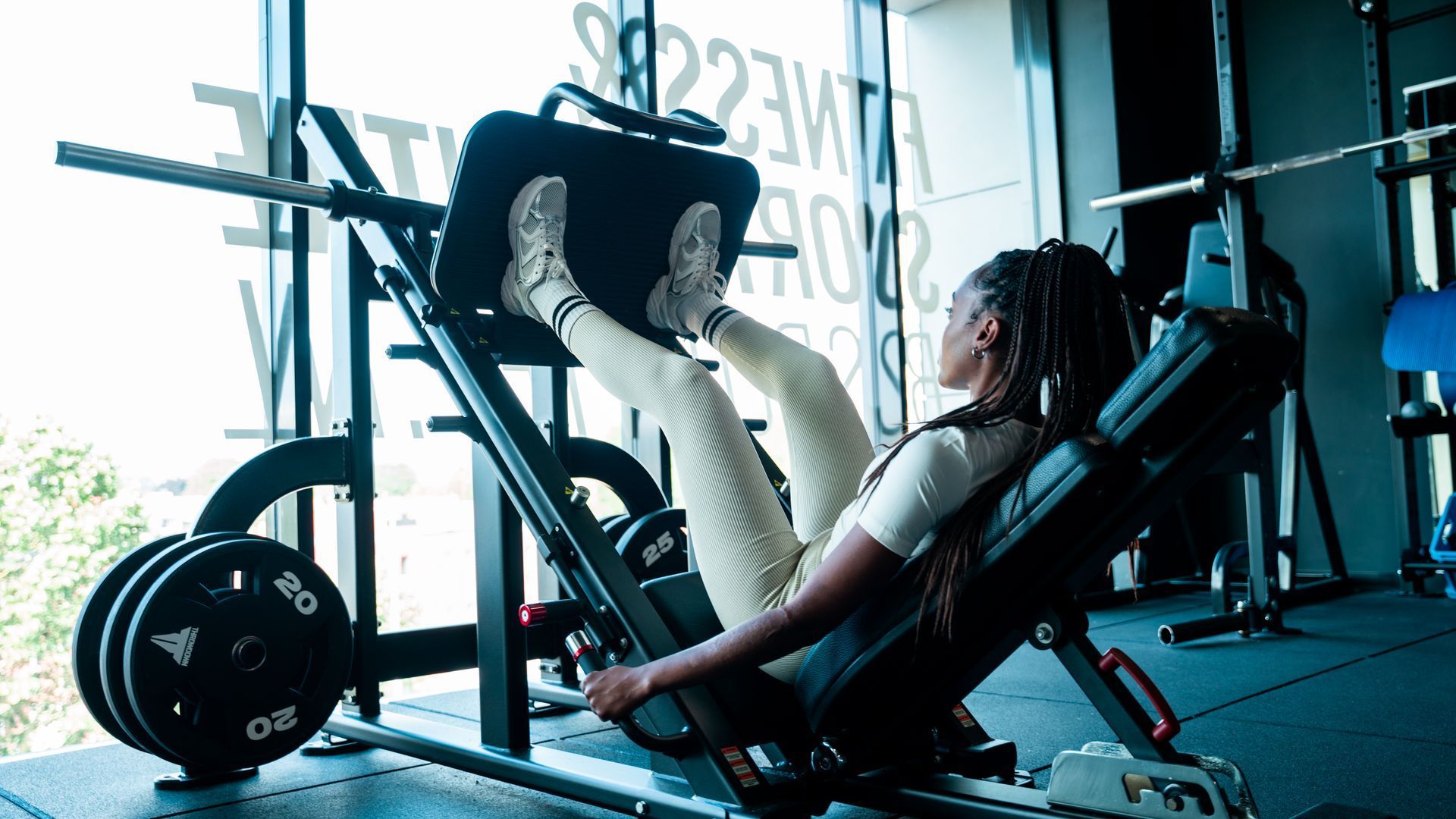 Een vrouw zit op een leg press-apparaat in een sportschool.