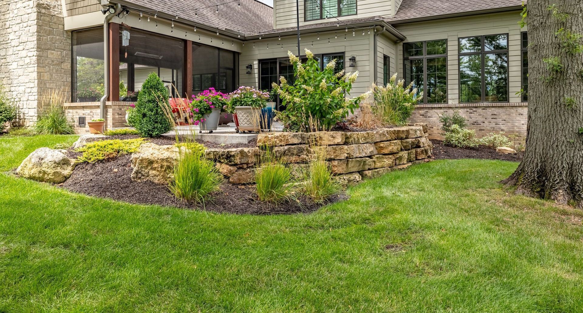 A large house with a lush green lawn and a stone wall in front of it.