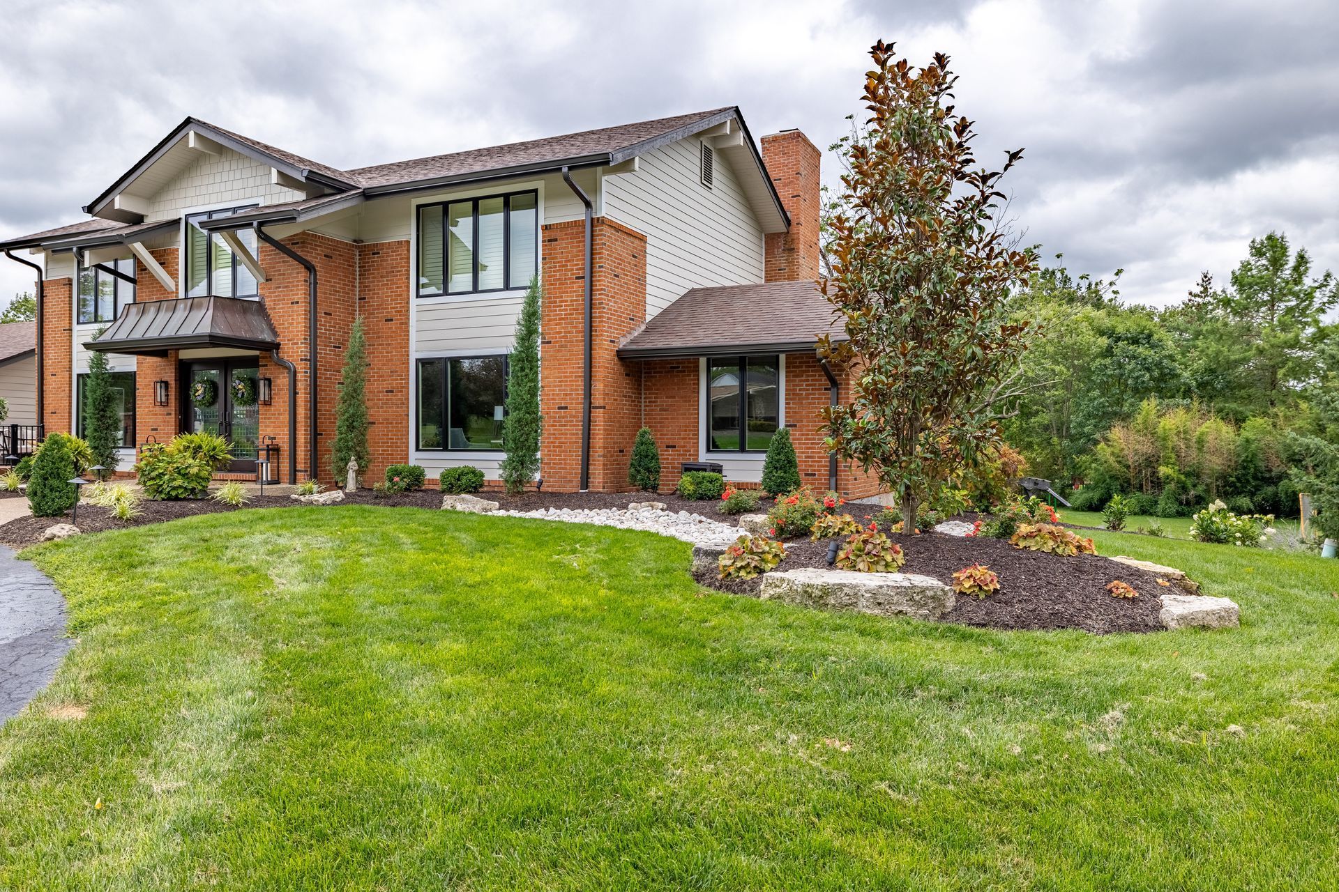 A large brick house with a lush green lawn in front of it.