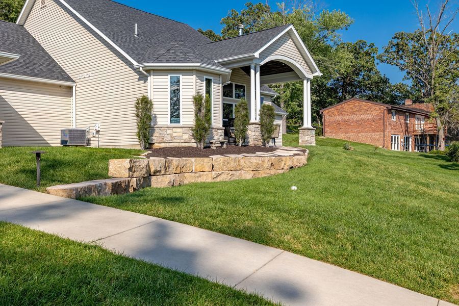 A house with a lush green lawn and a sidewalk in front of it.