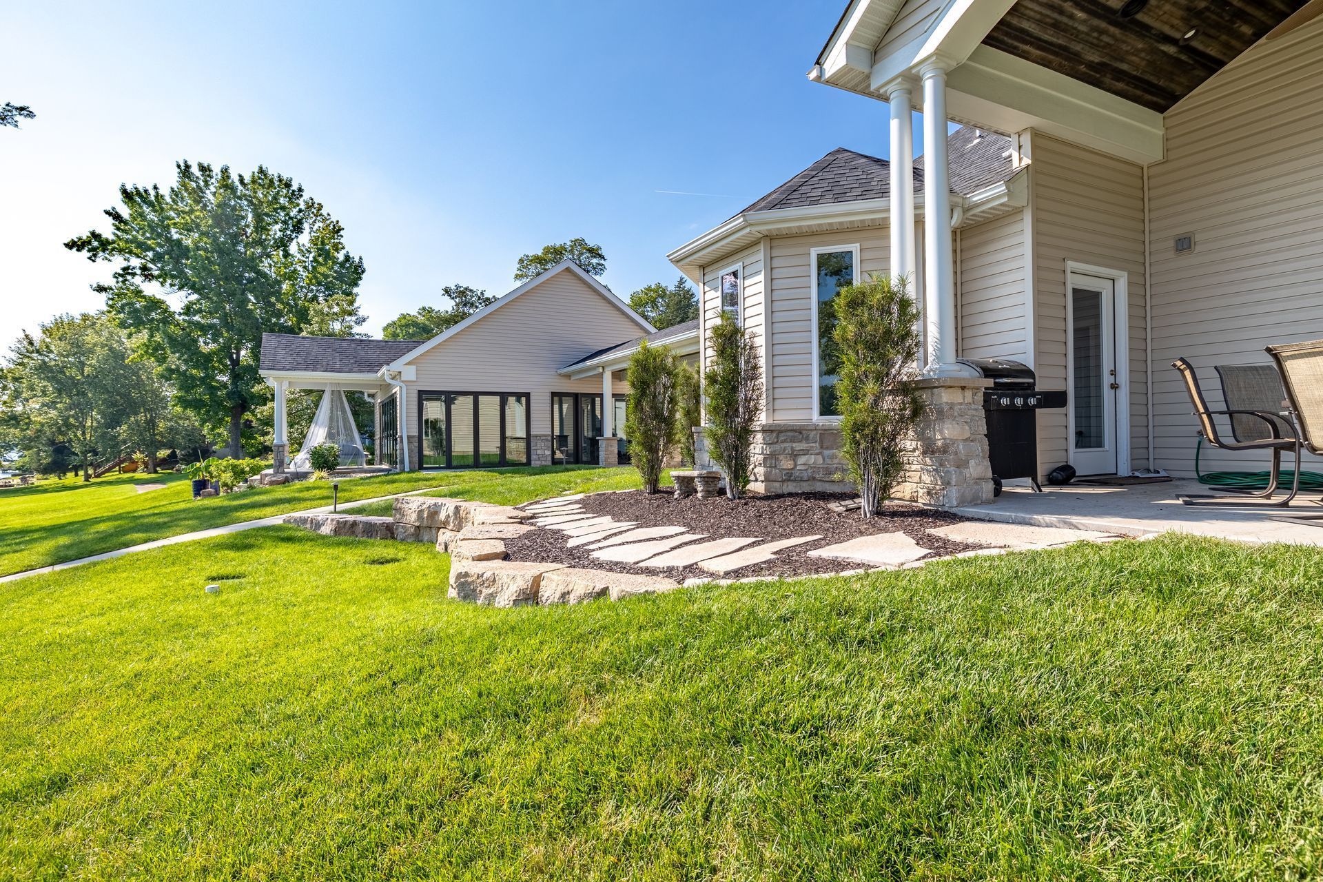 A house with a large lawn and a patio in front of it.