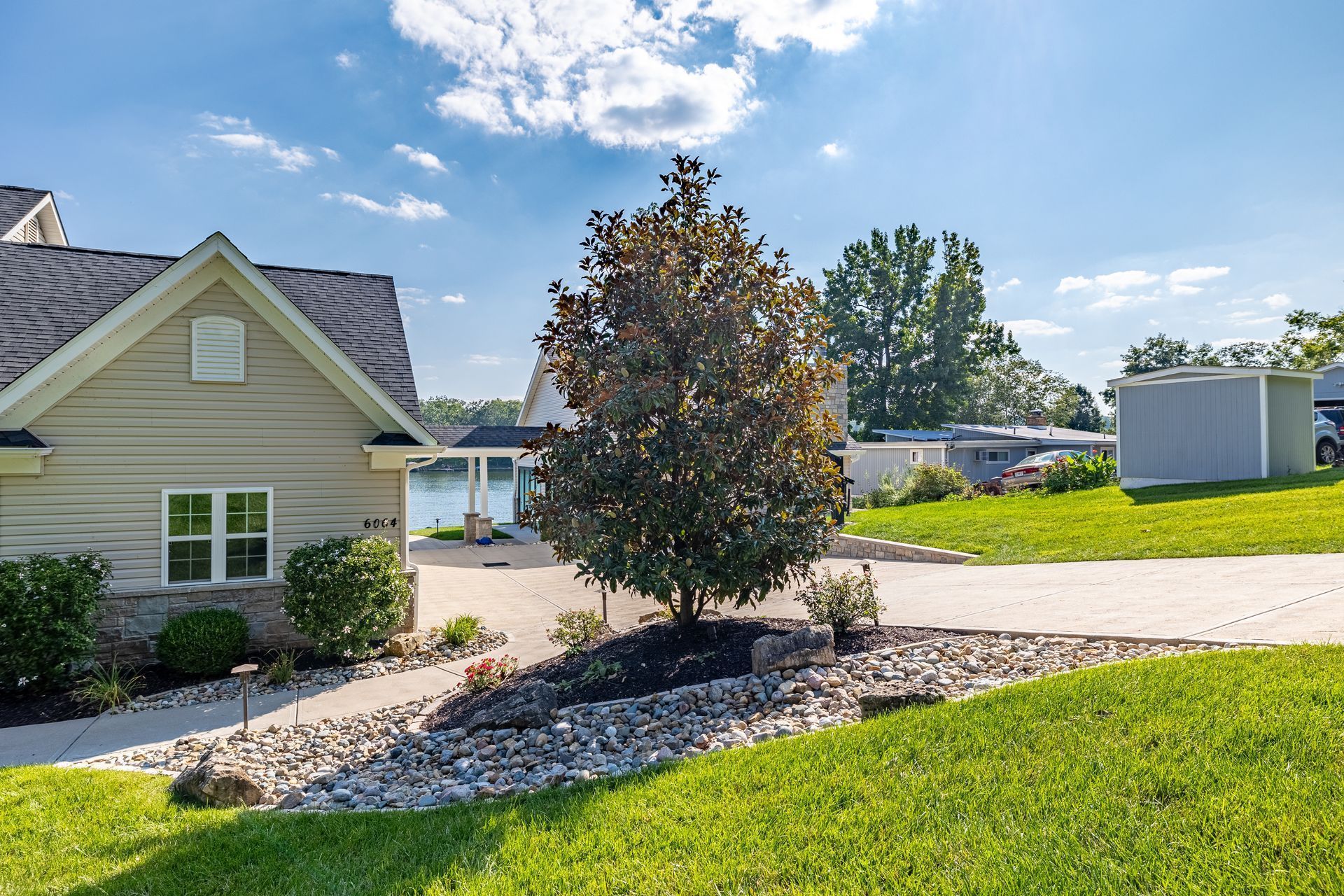 A house with a lot of grass and a tree in front of it.