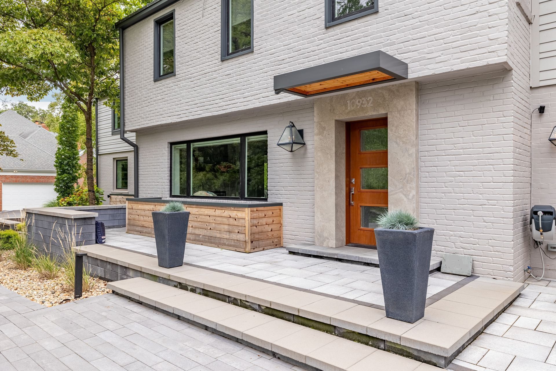 A large white brick house with a wooden door and potted plants in front of it.
