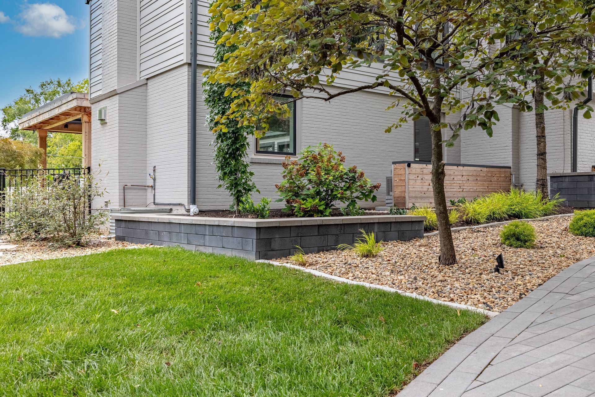 A white house with a lush green lawn and a tree in front of it.