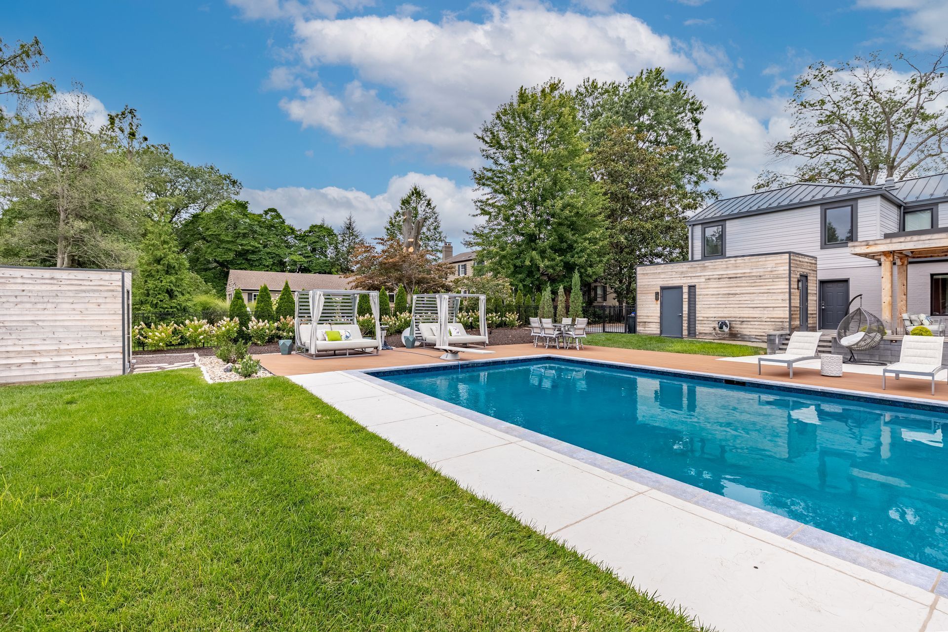 There is a large swimming pool in the backyard of a house.