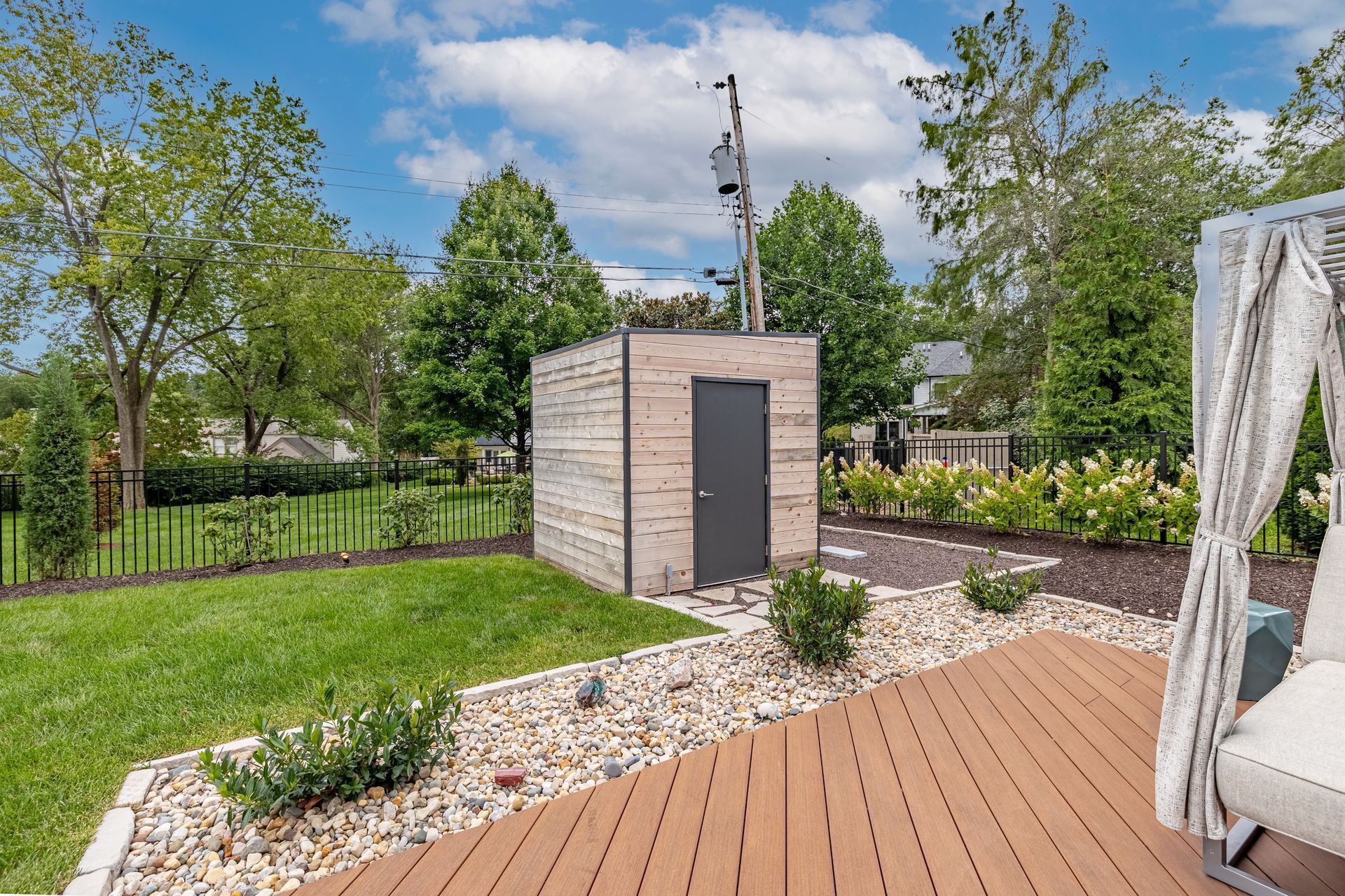 A wooden deck with a chair and a shed in the backyard.