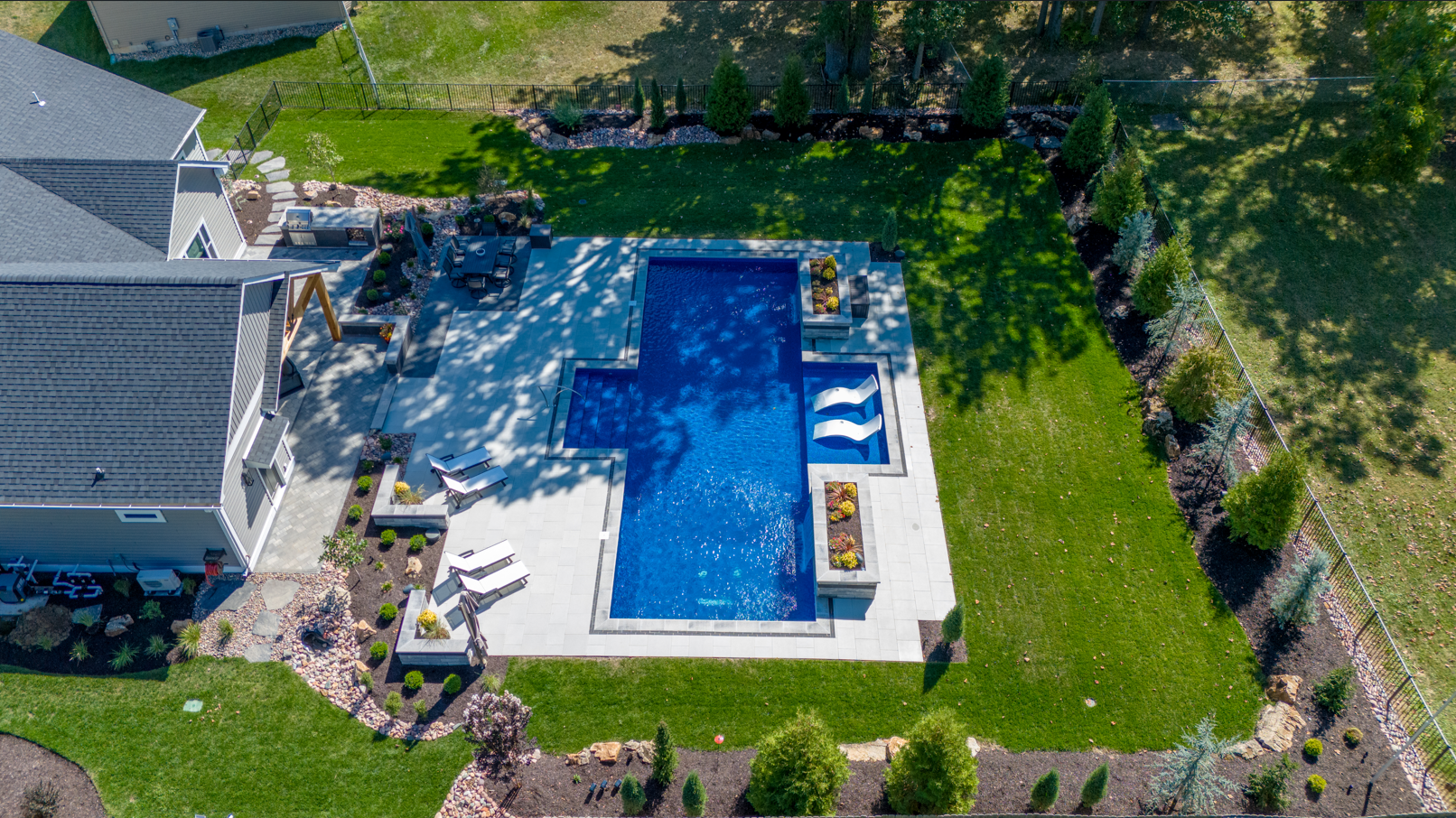 An aerial view of a large swimming pool in the backyard of a house.