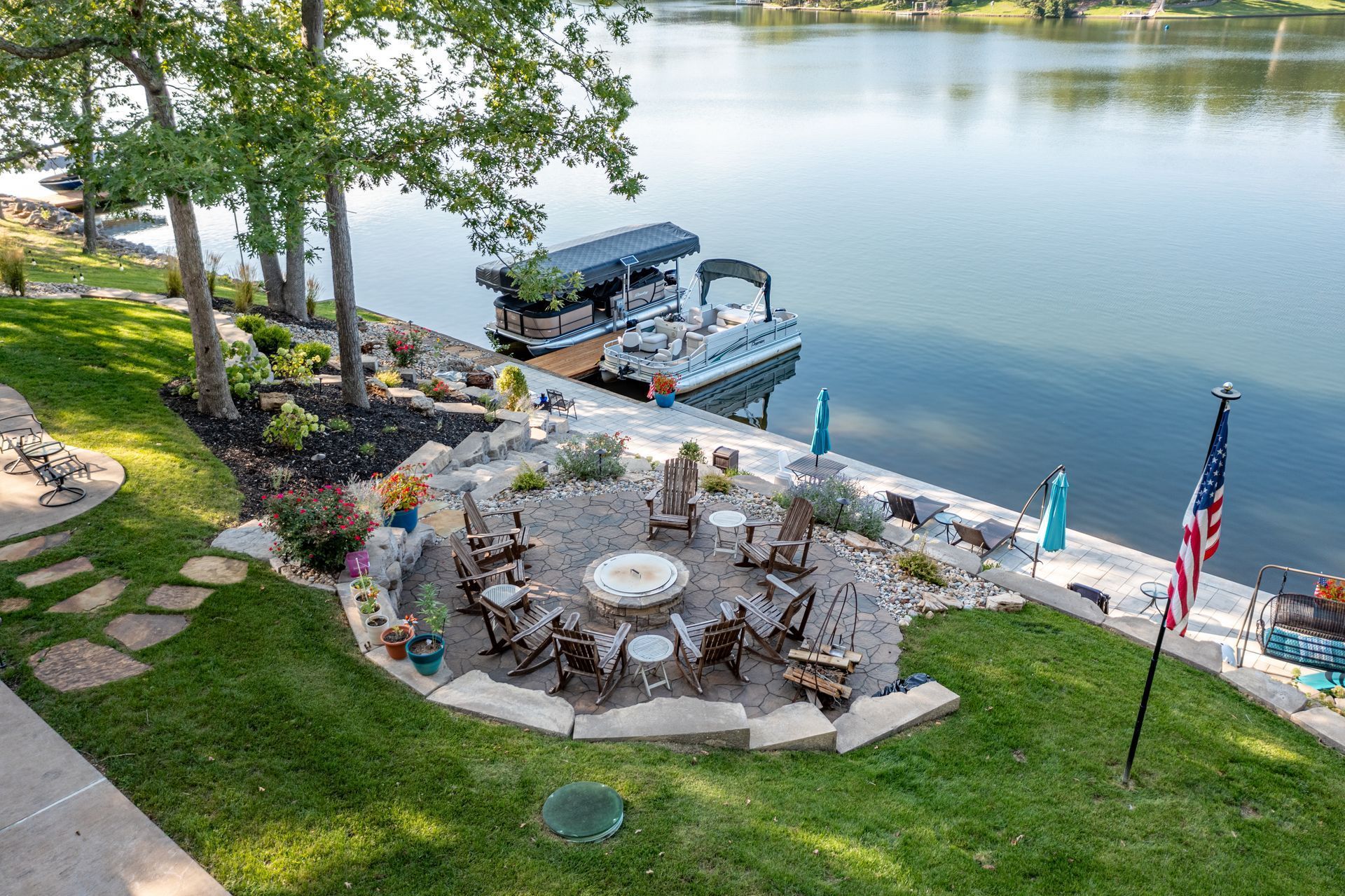 There is a fire pit in the middle of the yard next to a lake.