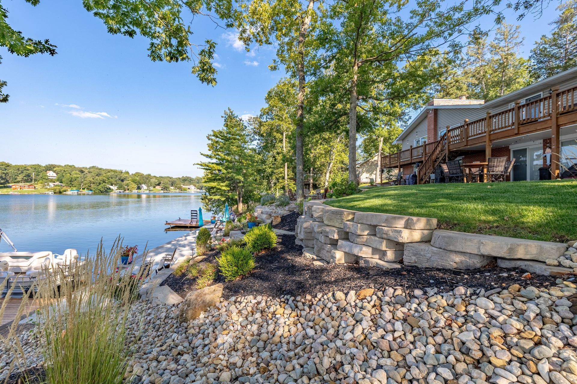 A house is sitting on the shore of a lake next to a rock wall.