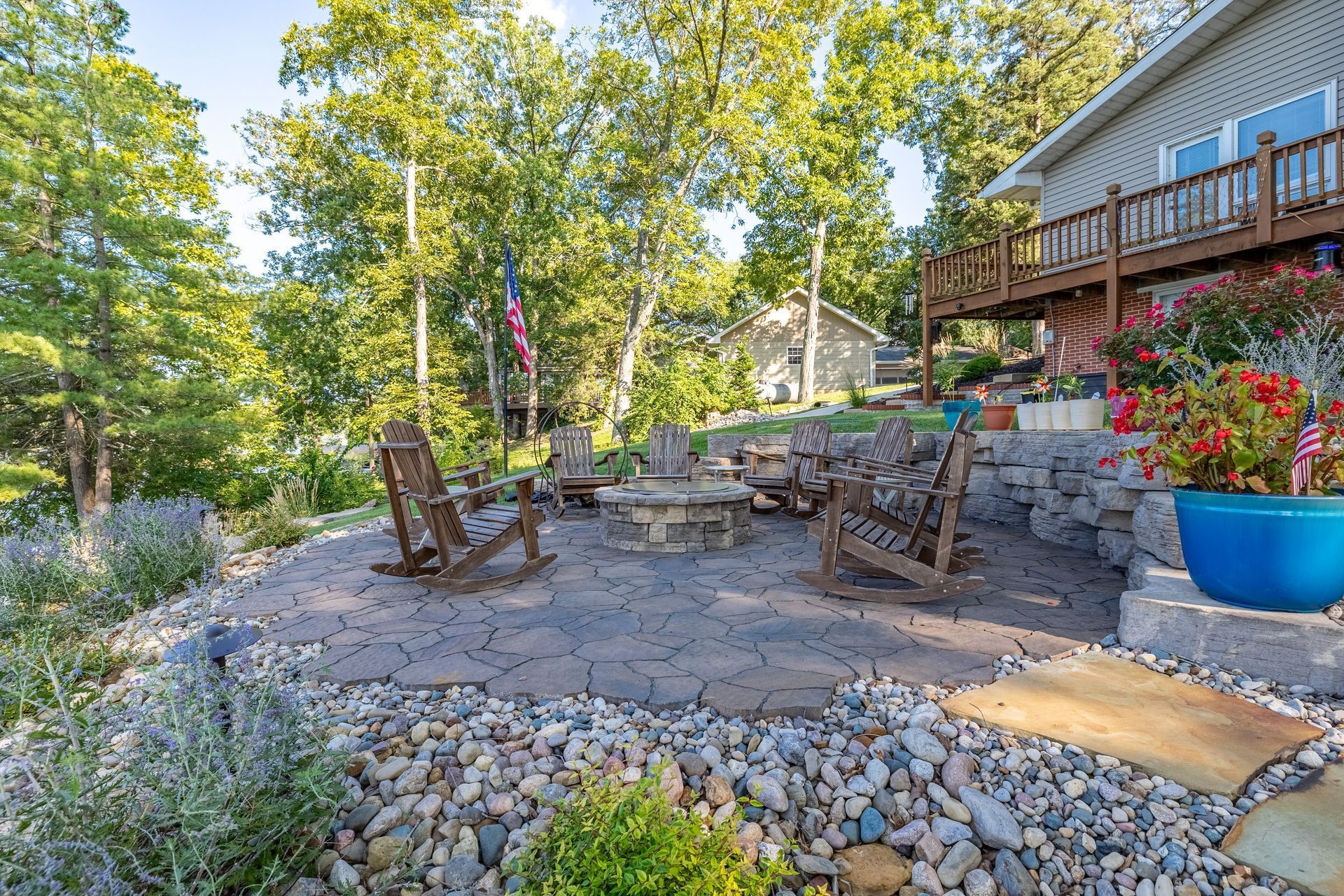 A patio with a fire pit and rocks in front of a house.
