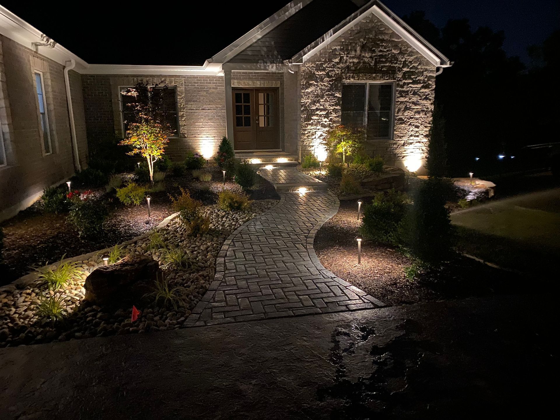 A house with a walkway leading to it is lit up at night.