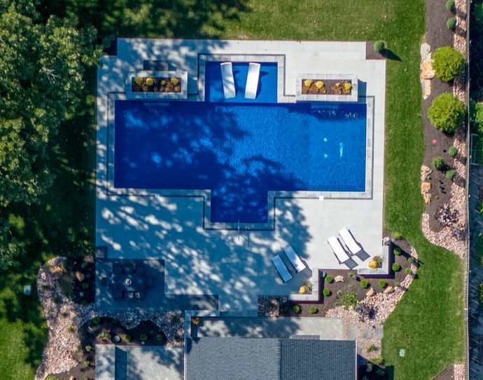 An aerial view of a large swimming pool in the backyard of a house.