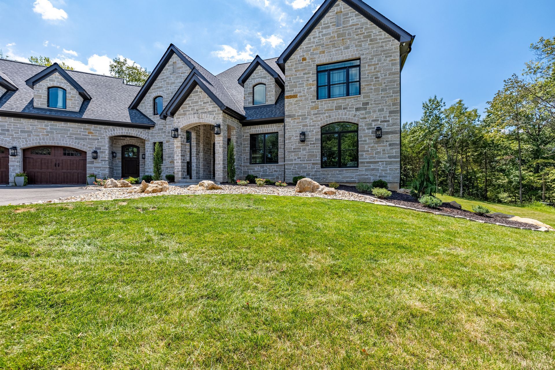 A large stone house with a large lawn in front of it.
