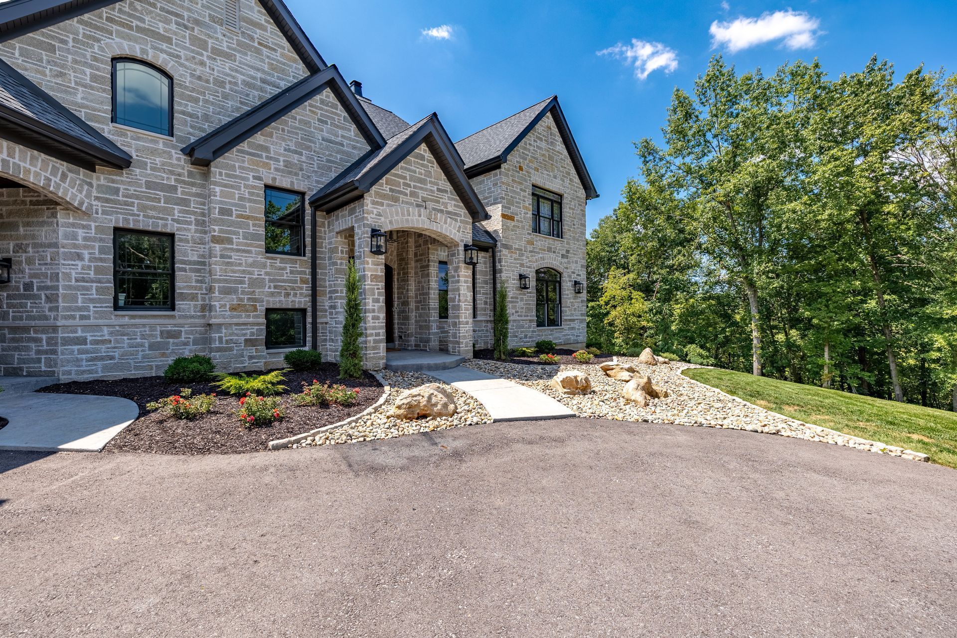 The front of a large brick house with a driveway leading to it.