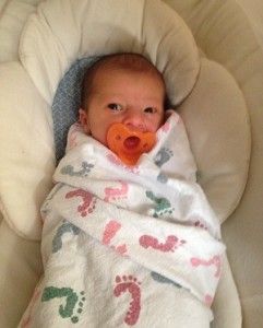 a baby wrapped in a blanket with a pacifier in his mouth .
