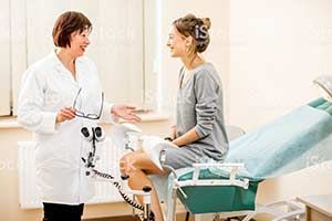 a woman is sitting in a gynecological chair talking to a doctor .
