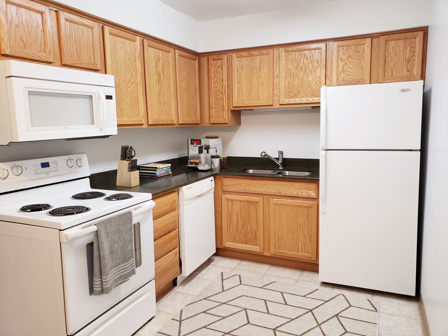 Apartments for Rent in Johnston- Elm Village- Wood-Style Cabinets with Black Countertops and Modern Appliances