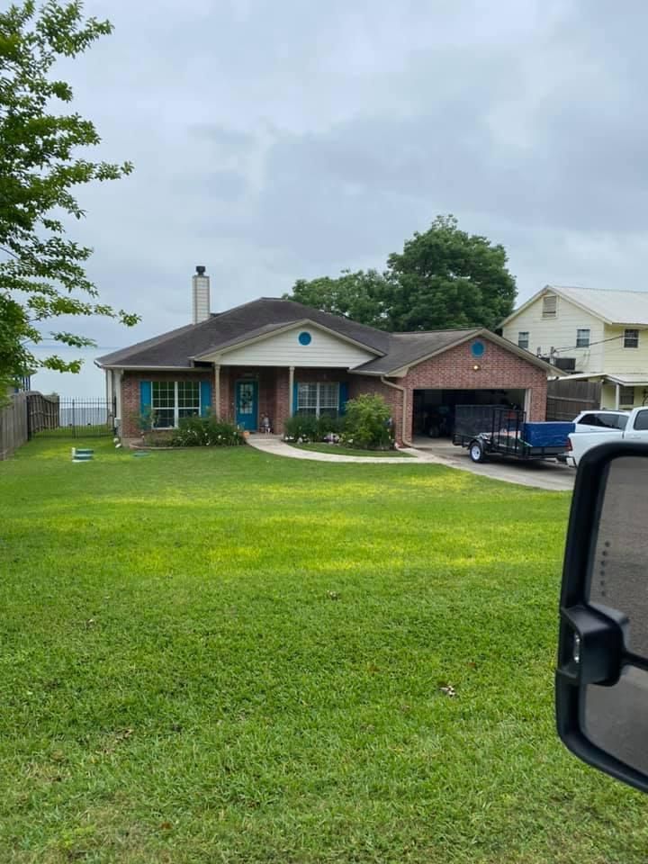 A single-story brick house with blue shutters and a green lawn under an overcast sky.