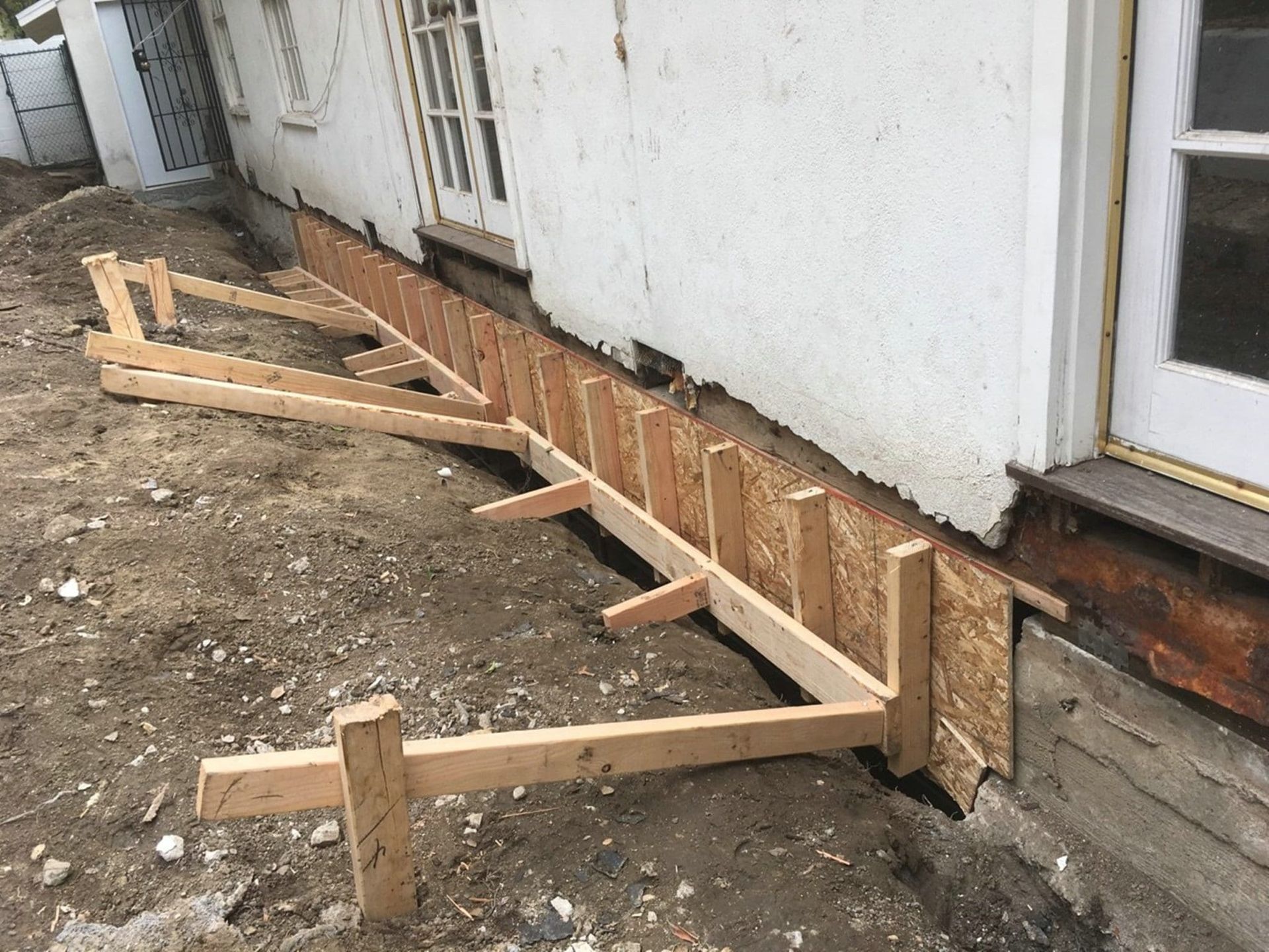 Wooden forms built against a white building's foundation, likely for concrete work.