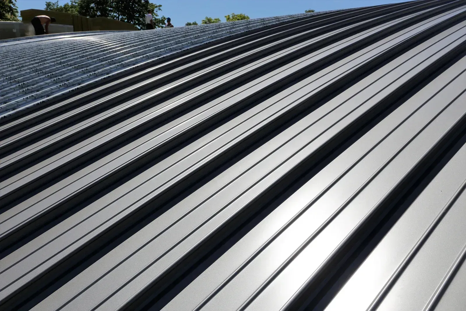 Gray metal roof with curved ridges reflecting sunlight.