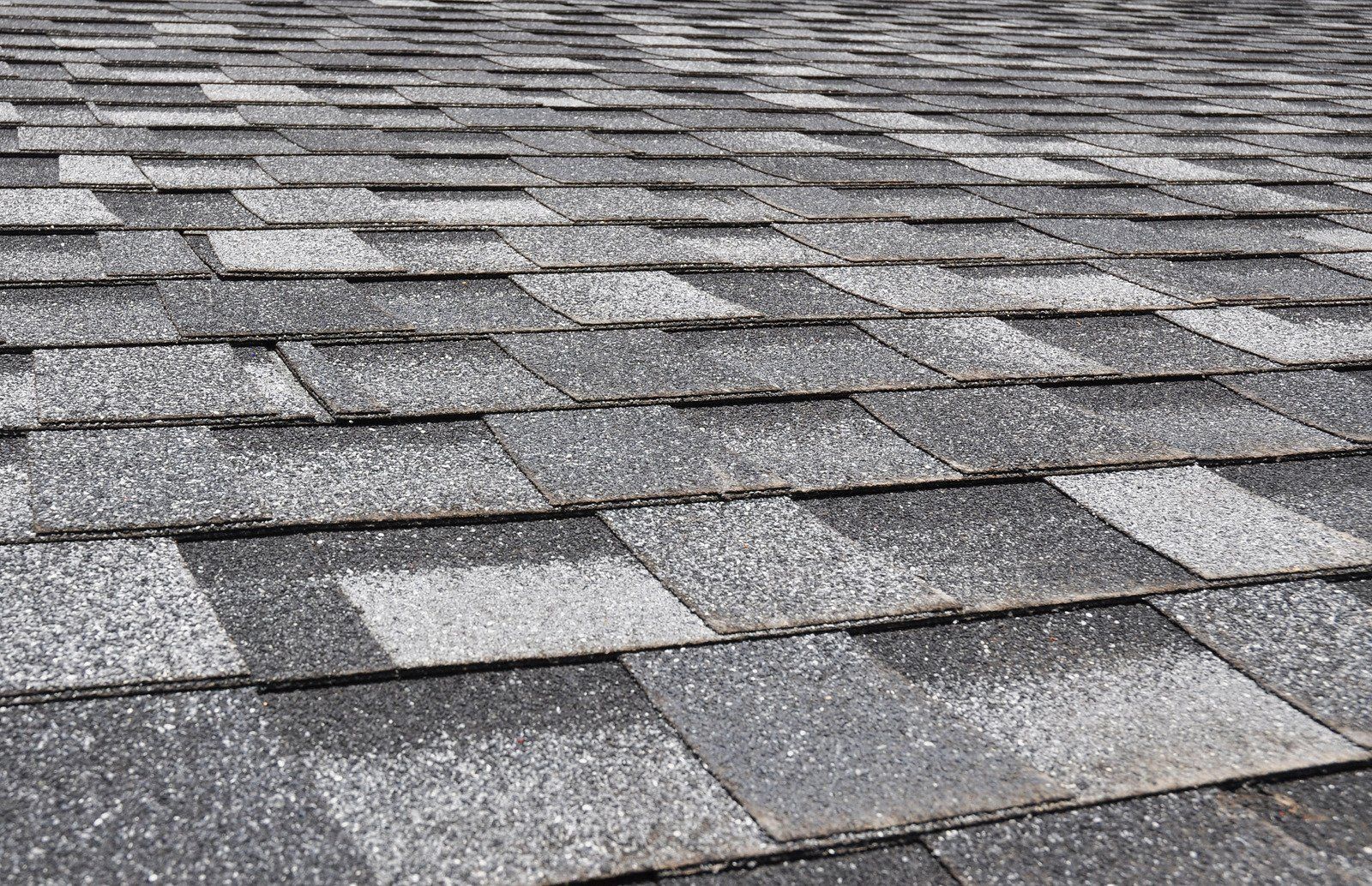 Close-up view of a shingle roof in shades of gray, showing overlapping tiles.