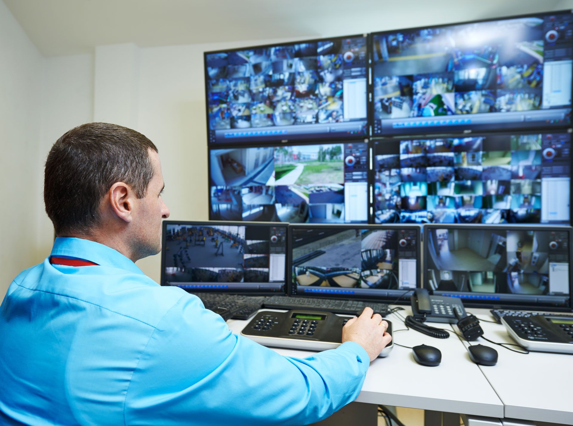 A man is sitting at a desk in front of a bunch of monitors.