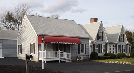 Gray building with red awning and black asphalt driveway.