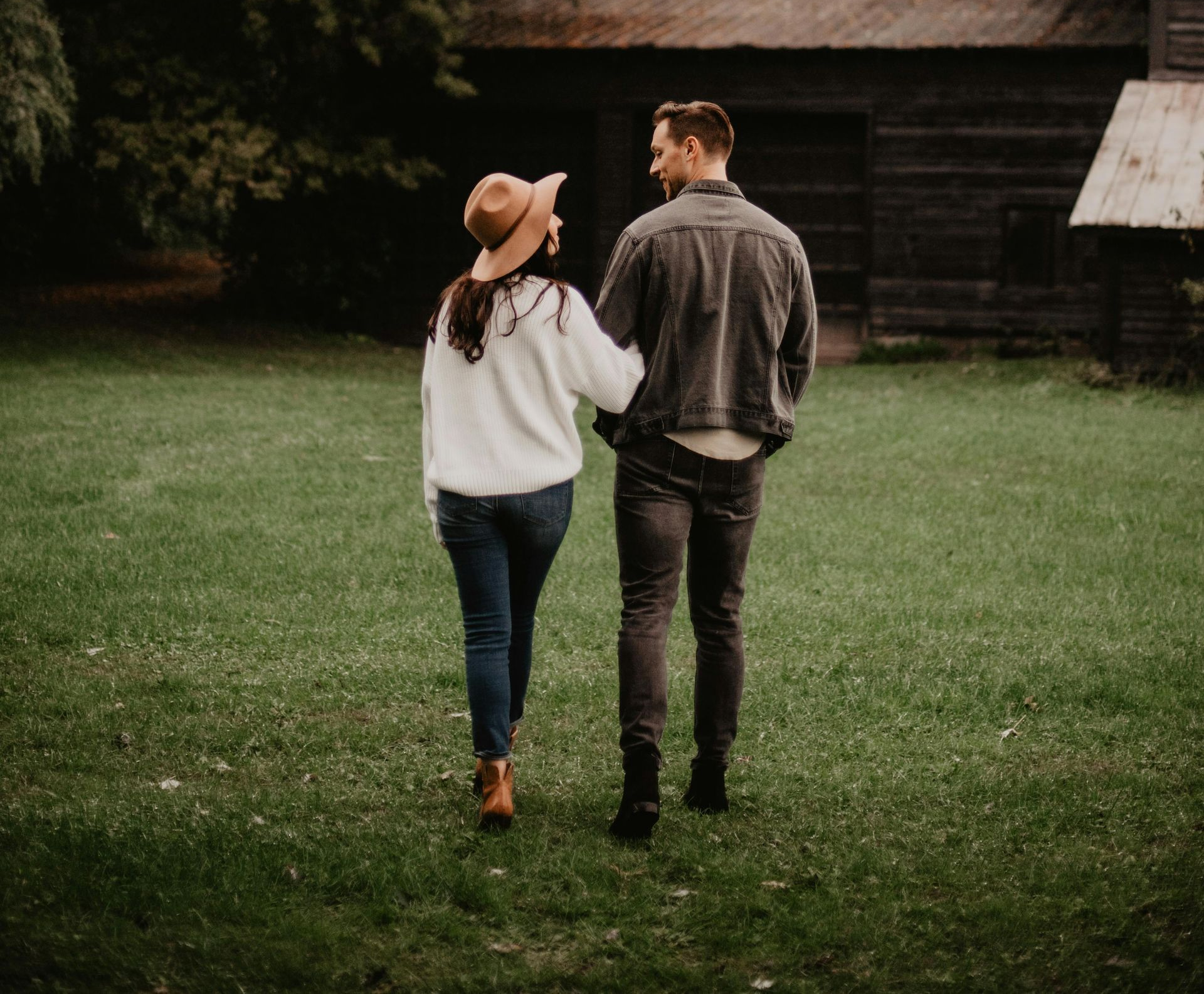 A man and a woman are sitting on a couch looking at a laptop computer.