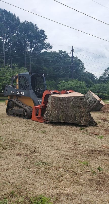 A bulldozer is cutting a tree stump in a field.