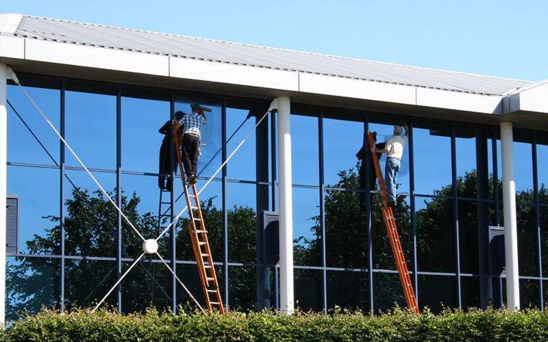 Two men are cleaning the windows of a large building