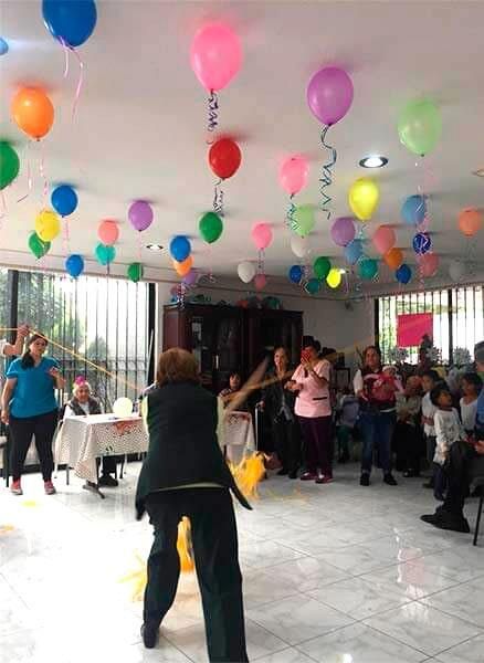 Un grupo de personas está bailando en una habitación con globos colgando del techo.