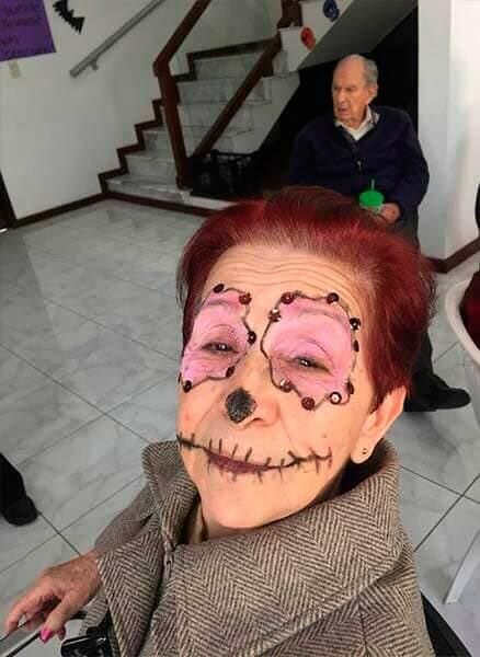Una mujer en silla de ruedas tiene una cara de esqueleto pintada en su cara.