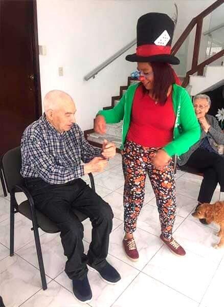 Una mujer con sombrero de copa está de pie junto a un hombre en una silla.