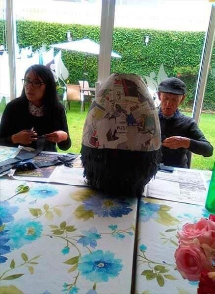 Un hombre y una mujer están sentados en una mesa haciendo un animal de peluche.