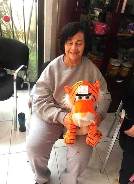 Una mujer está sentada en una silla sosteniendo un tigre de peluche.