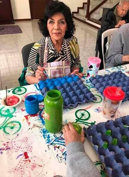 Una mujer está sentada en una mesa pintando con un niño.