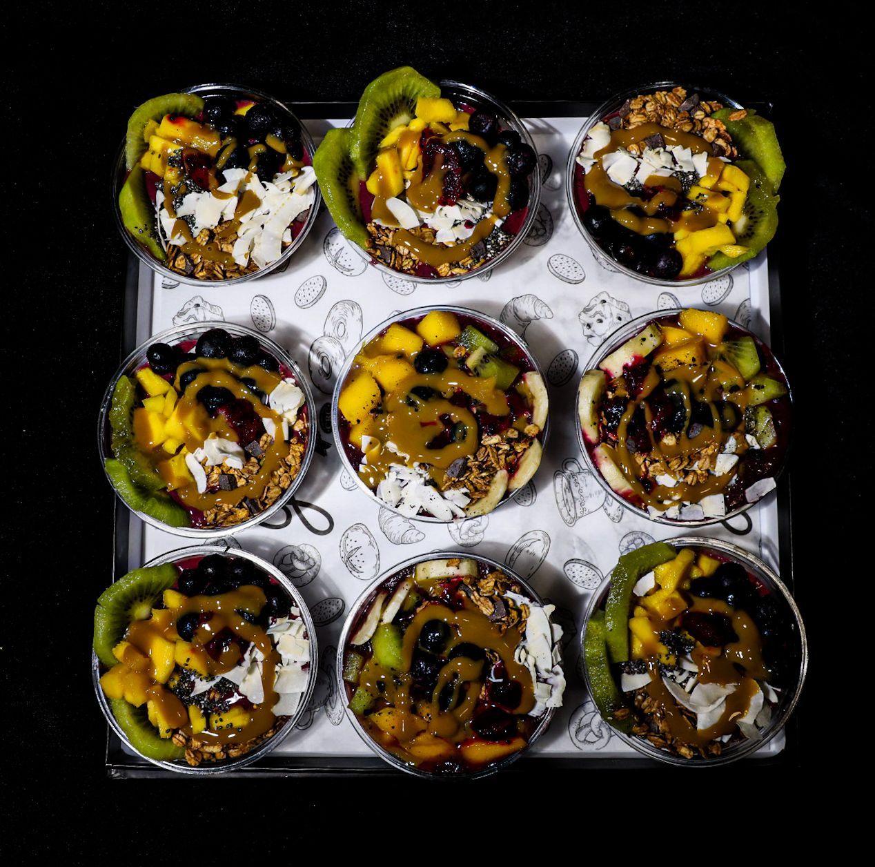 A tray of cupcakes filled with fruit and granola on a table.