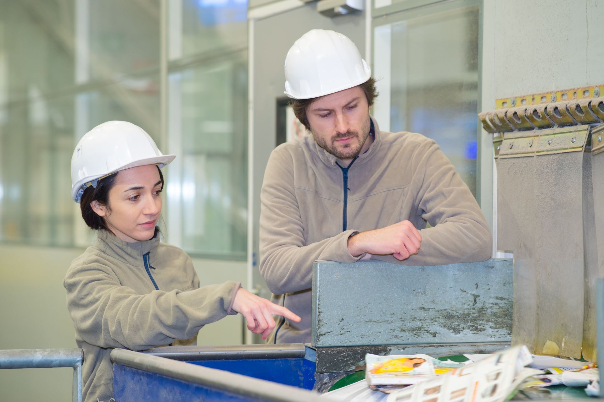 Workers sorting materials at commercial recycling center with bins and industrial equipment.