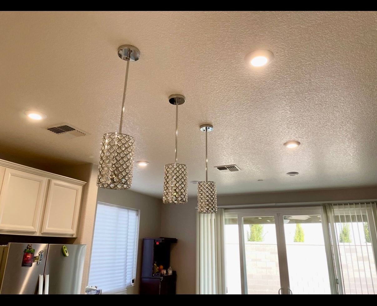 Illuminated home at dusk; pathway leads to the front door, two people stand near the door.