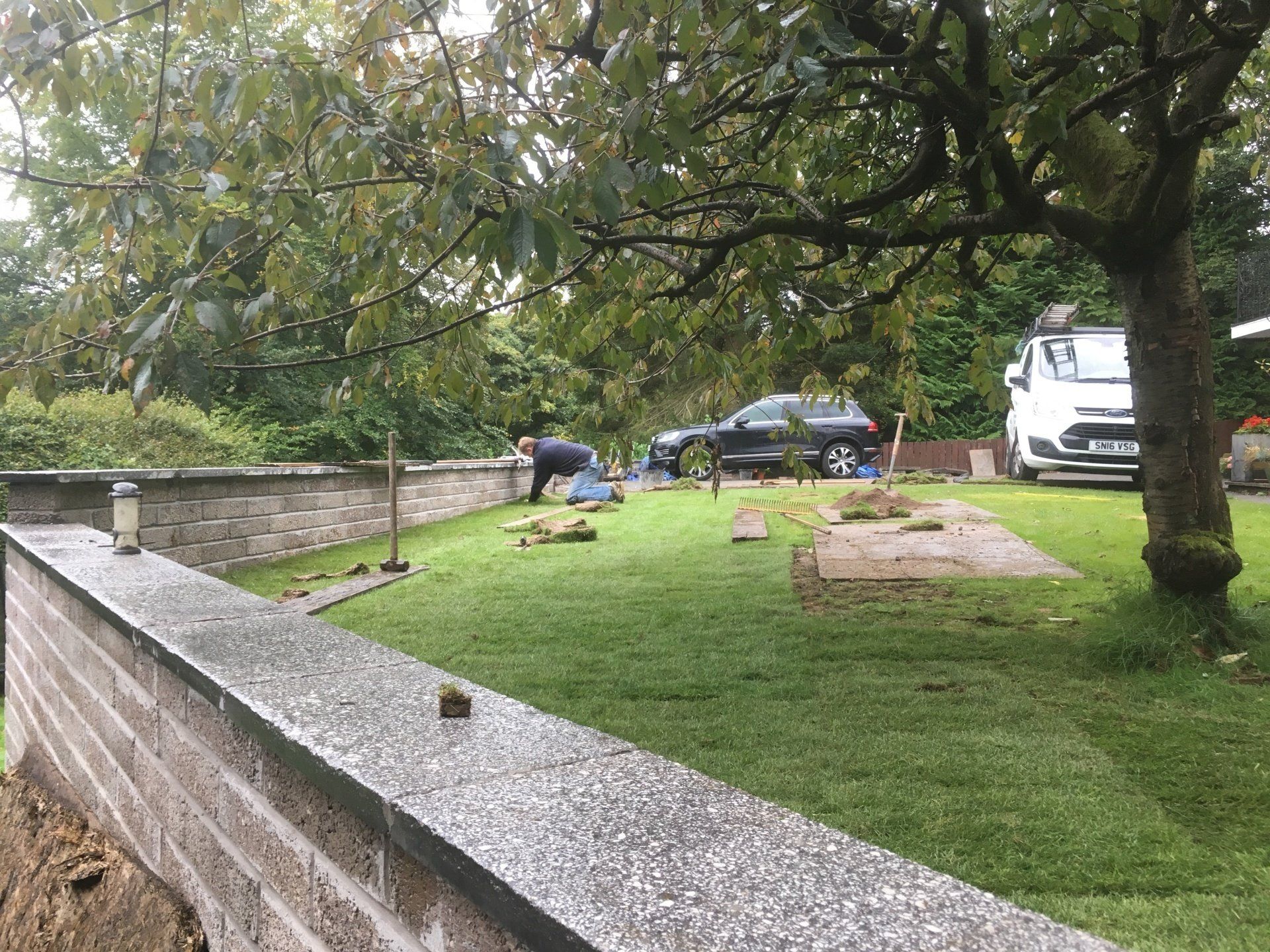 man laying turf near a wall