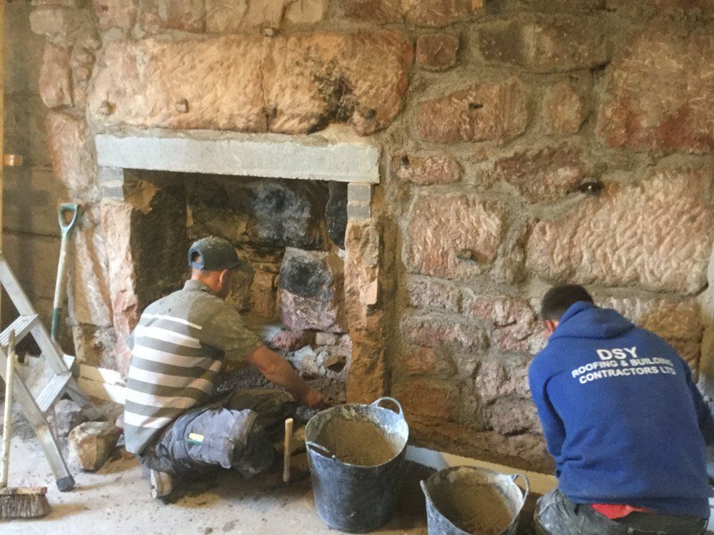 2 men repairing sandstone wall and fireplace