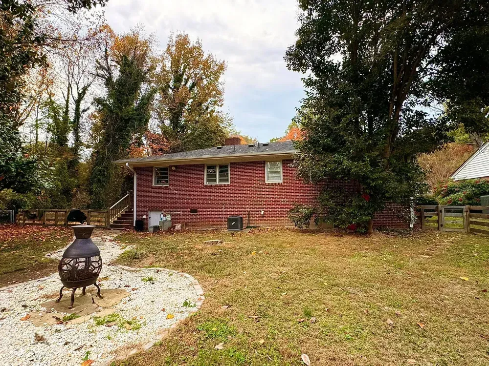 A brick house with a fire pit in the backyard.