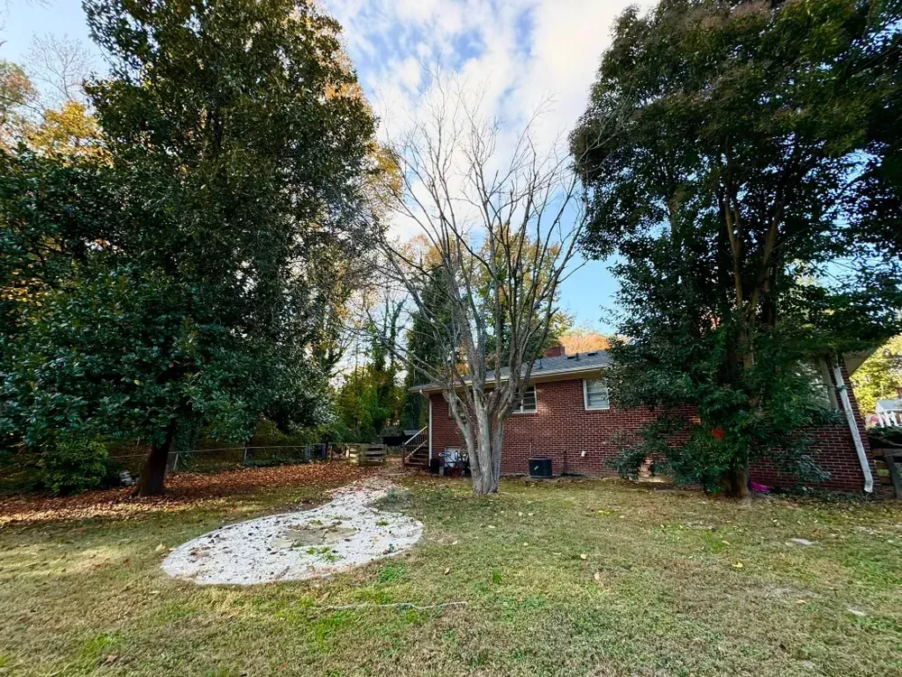 A backyard with a brick house and trees in the background.