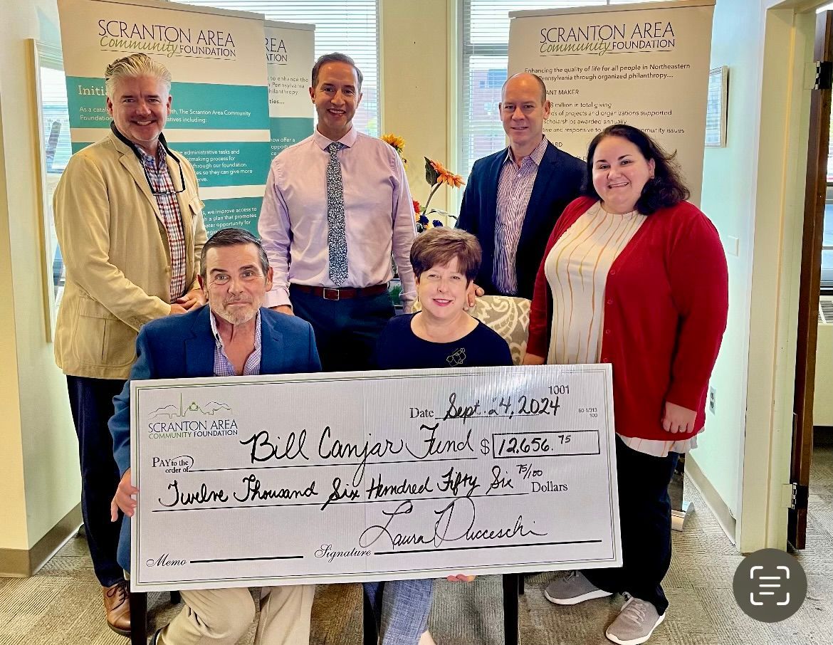 A group of people standing around a large check.