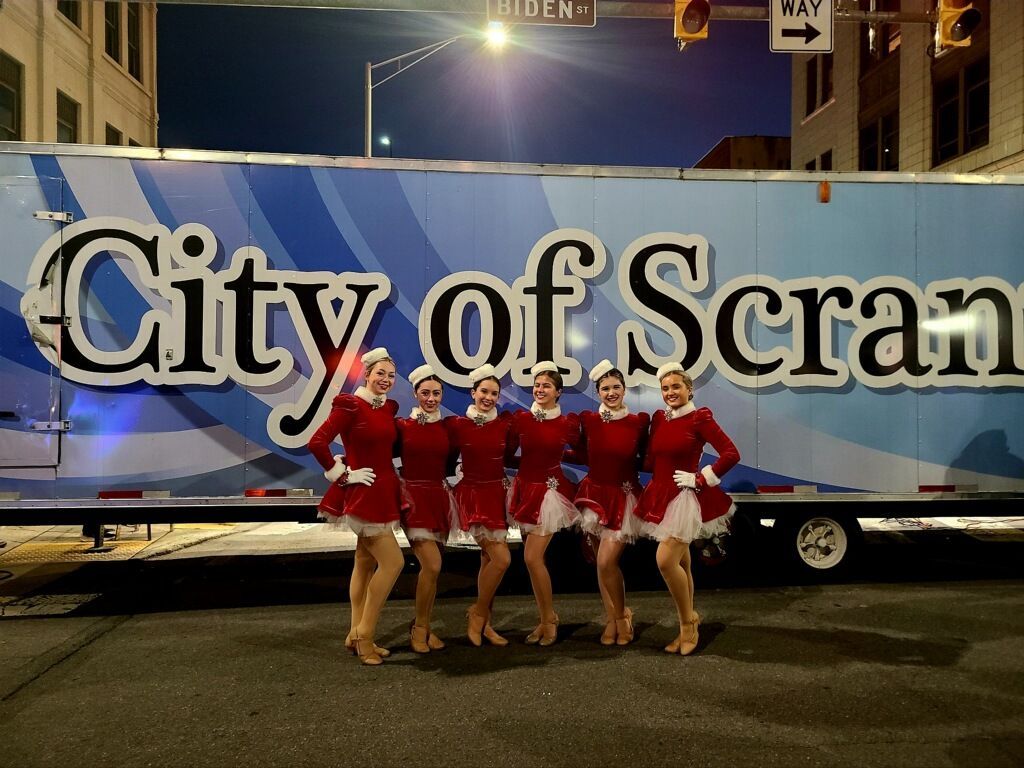 A group of women are posing in front of a city of scranton truck
