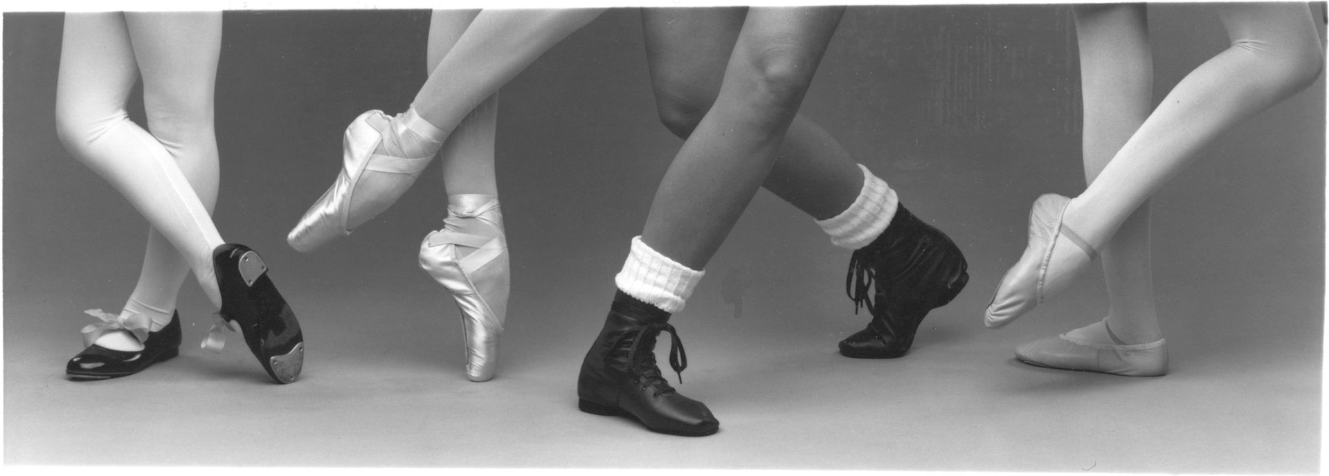 A black and white photo of a group of dancers ' feet