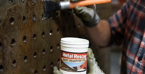 A person is holding a can of metal rescue and a brush.